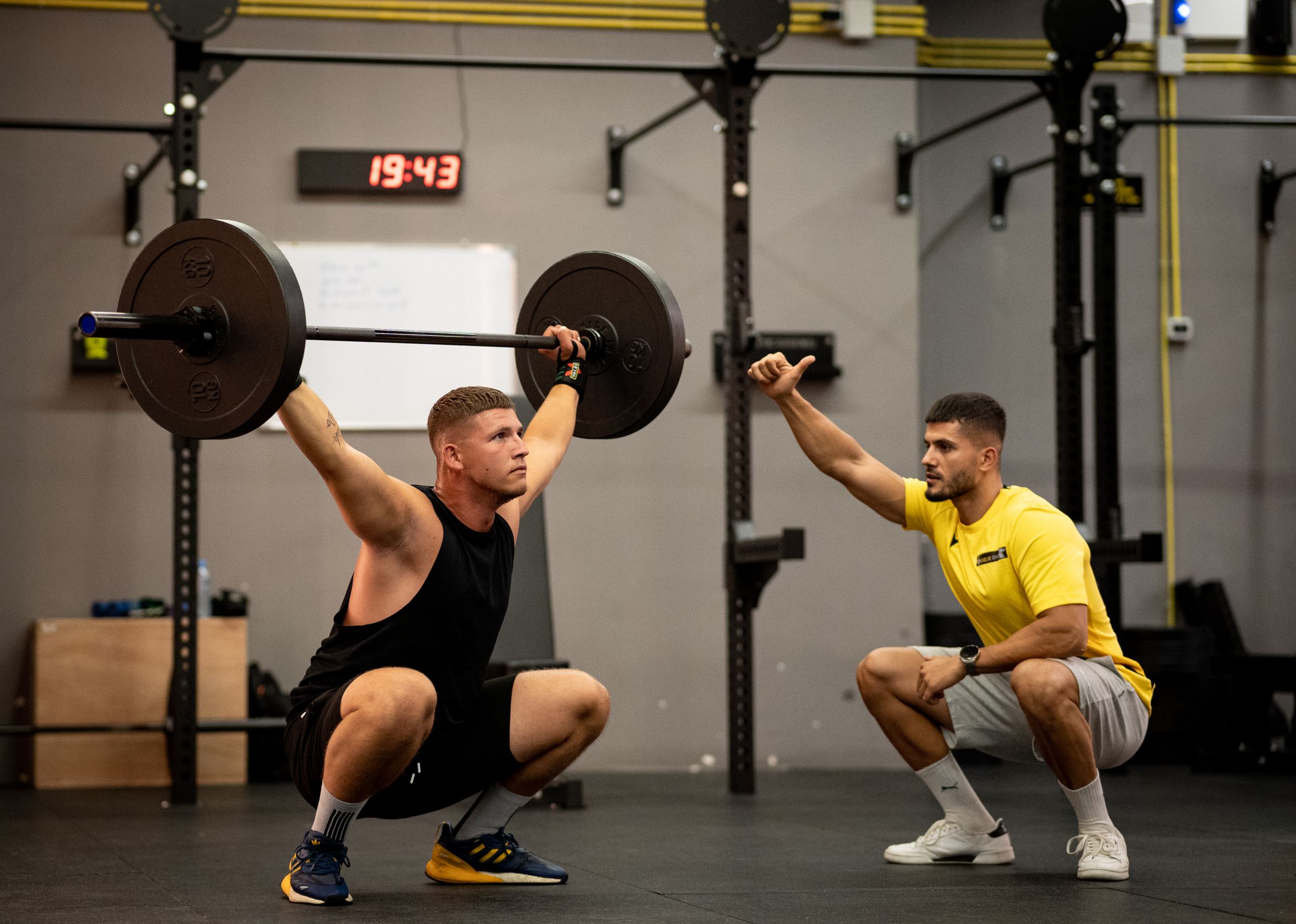 Trainer spotting woman squat
