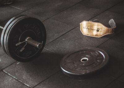 A heavy barbell and weightlifting belt on a gym floor, emphasizing strength and fitness.